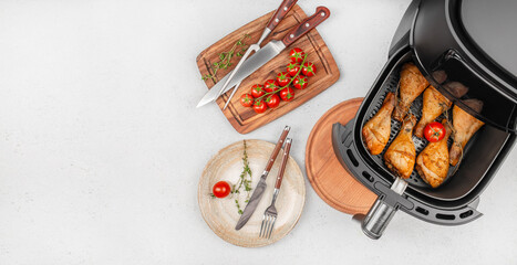 Air fryer chicken drumsticks with fresh tomatoes and herbs on a modern kitchen countertop. top...