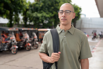 Hispanic man tourist in Thailand with backpack and tuk tuk taxis exploring Southeast Asia