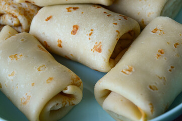 close-up hand holding rolled pancake crepe filled with sweet savory filling light blue plate homemade comfort food traditional cooking comfort food breakfast recipes family meals