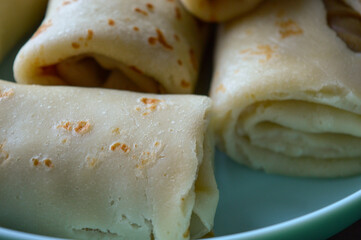 close-up hand holding rolled pancake crepe filled with sweet savory filling light blue plate homemade comfort food traditional cooking comfort food breakfast recipes family meals