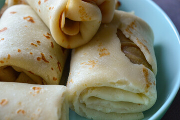 close-up hand holding rolled pancake crepe filled with sweet savory filling light blue plate homemade comfort food traditional cooking comfort food breakfast recipes family meals