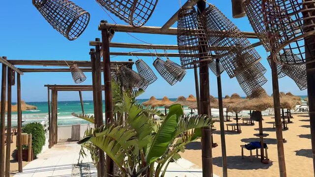 Rustic beach caf&eacute; with bamboo chairs and wooden lampshades in sunny Puglia, southern Italy. Tropical flowers sway in the sea breeze, capturing Mediterranean coastal charm