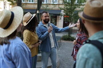 Guide with microphone and group of tourists on city street during excursion