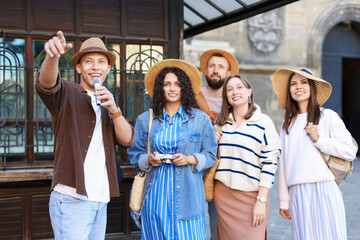 Guide with microphone and group of tourists on city street during excursion