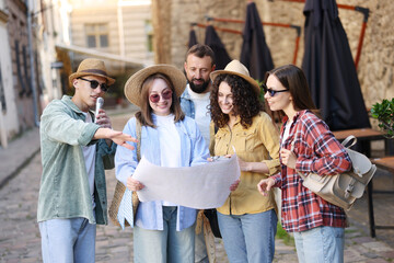 Guide with microphone and group of tourists on city street during excursion