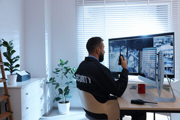 Security guard monitoring CCTV cameras in office, back view