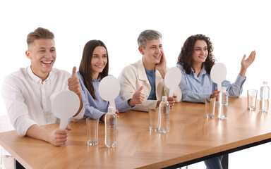 Panel of judges with blank score signs at table on white background