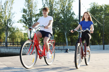 Naklejka premium Teenage girl and boy riding bicycles on city street