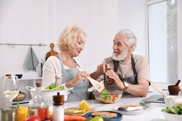 Elderly couple cooking together at table indoors