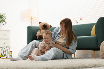 Fototapeta premium Happy mother spending time together with her son on floor at home