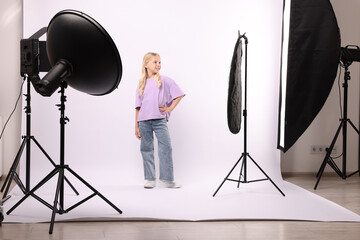 Little girl on white background in photo studio with professional equipment