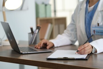 Telemedicine. Doctor making notes while having video call with patient via laptop indoors, closeup