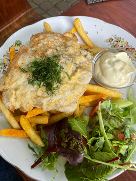 Tasty fried latvian pork chop or karbonade served with seasoned fries, fresh salad and mayonnaise dressing. Garnished with fresh dill for flavor and presented on traditional rustic vintage plate