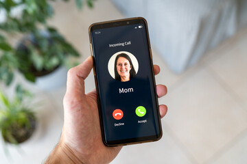 Boy holding smartphone while his mother is calling him. Concept of incoming call from mom.