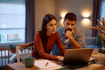 Young couple using laptop while going through their home finances.