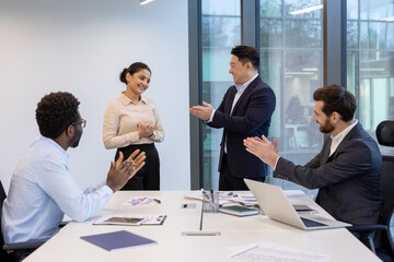 Employees engaging in a professional meeting, applauding colleague for achievements, fostering teamwork.