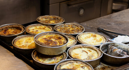 A tray full of small round molds with already baked pies