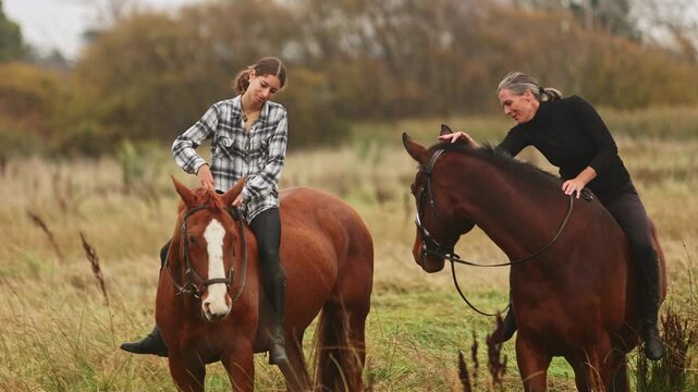 Two women horse riding in autumn field