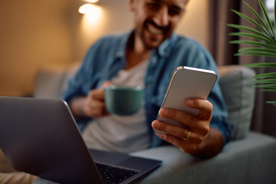 Close up of man using app on smart phone at home. - Powered by Adobe