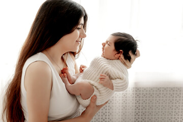 a mother holds a baby in her arms, admiring and kissing it, the birth of a baby, parental love and care, mother and baby