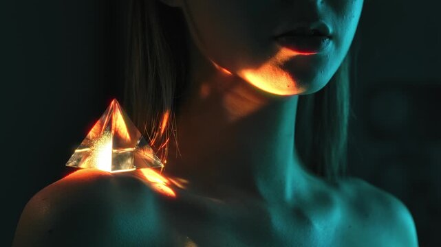 Glass prism reflecting light on woman shoulder in artistic low key setup
