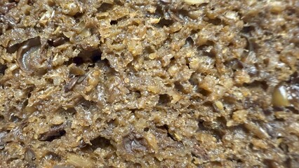 close up of dense moist dark rye bread texture with visible grains and seeds ideal for food packaging or bakery background

