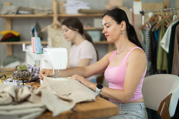 Sewing workshop work - two female tailors sewing dresses on sewing machines