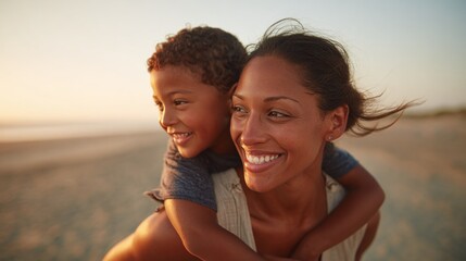 A mother carrying her young son on her back, both smiling and looking off into the distance, enjoying a sunset at the beach.