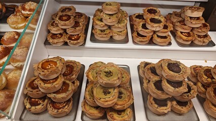 Assorted Spanish pastries and filled buns displayed in a bakery showcase with rich toppings and textures