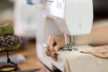 Young seamstress working on modern sewing machine in sewing workshop