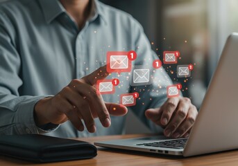 Man interacting with email notifications using a laptop on a wooden desk in a bright environment