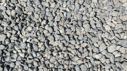 Top-down view of dense surface of gray, angular stones or gravel. Suitable for use as a background or for themes of construction, geology and landscaping