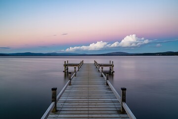 Obraz premium Tranquil water reflecting pastel sunset sky from wooden pier for peaceful escape and calming nature scenes