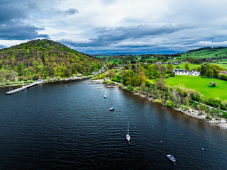 Obraz premium Farms and mountains over Ullswater Lake from drone, Pooley Bridge, Lake District National Park, Cumbria, England