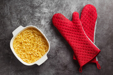 Spiral macaroni in ceramic dish and oven mitts