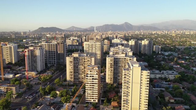 Atardecer dorado sobre los edificios de Macul, con sombras largas y cielo c&aacute;lido en Santiago de Chile
