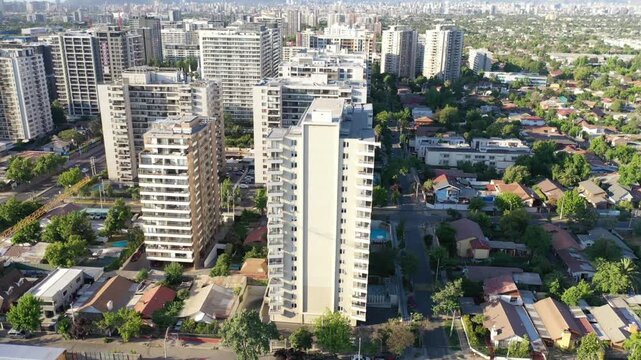 Atardecer dorado sobre los edificios de Macul, con sombras largas y cielo c&aacute;lido en Santiago de Chile