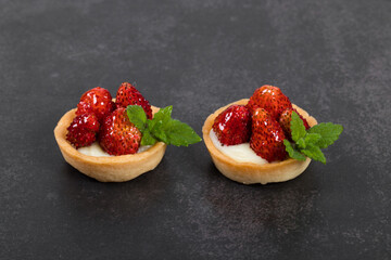 Two Round Strawberry tartlets. Dark gray background. Close up