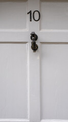 Front door with number ten 10. Closeup of house entrance with classic door knocker on famous political address background