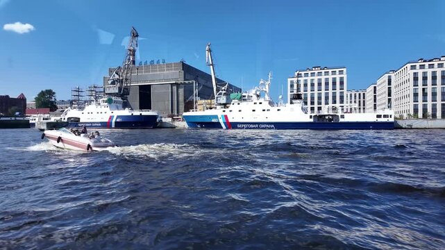 A boat speeds along the Neva River past the Almaz shipyard on a clear sunny day - St. Petersburg, Russia, July 16, 2025