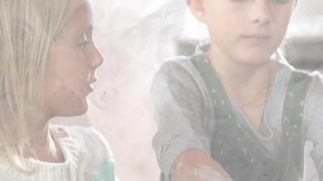 Gazing at spinning clay lump, two girls pressing, shaping cylinder on pottery wheel for art class