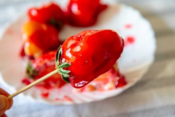 The best sweet in the world, the iconic dessert strawberry of love on a stick, fresh strawberry, powdered milk brigadeiro and red caramel topping. Morango do amor