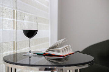 Glass of red wine and a book on the table