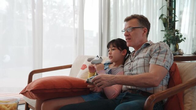 Granddaughter teaching grandfather play console game, entertainment hobby. Old senior use technology communicate with new generation kid cross generation gap strengthen family bond. Divergence.