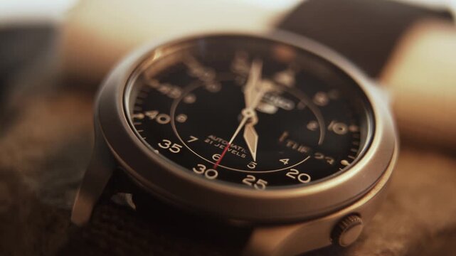 Macro close up of an automatic mechanical field watch with moving arms
