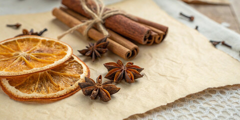 Fototapeta premium Dried orange slices, cinnamon sticks tied with twine, and star anise create a warm and inviting autumnal atmosphere on a textured background, perfect for evoking the scents and feelings of fall