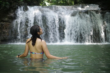 Fototapeta premium Female tourists exploring Siete Altares, which is a natural attraction located near Livingston, Guatemala, featuring seven freshwater pools and waterfalls set within a lush rainforest.