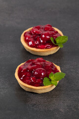 Two Vegan Cherry tartlets. Dark gray background. Close up