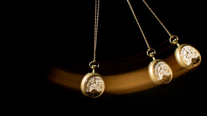 Antique pocket watch moving on a pendulum creating the illusion of multiple clocks, black background, selective focus.