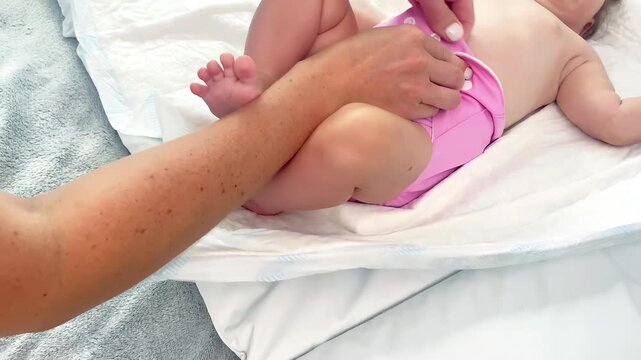 Mother changes textile multiple eco diapers to newborn baby.Little infant girl on changing table in eco friendly nappy.Mom taking care of child,motherhood daily routine.no waste disposal concept